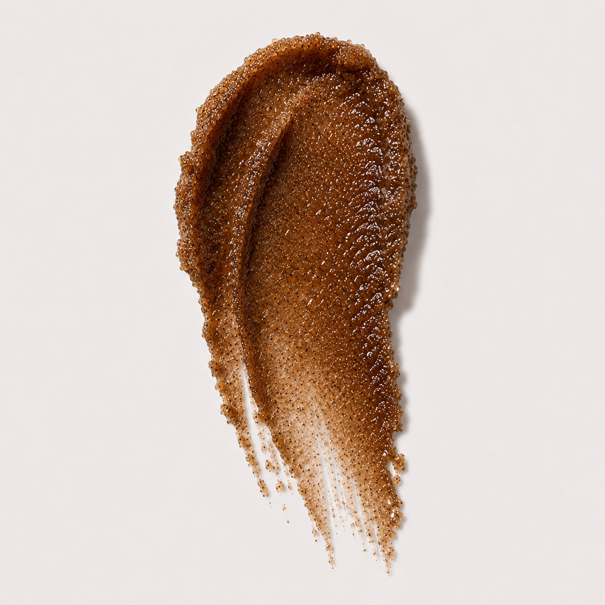 A textured swipe of coffee sugar scrub on a clean, light off-white background.