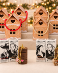 Six ABATURE gingerbread house gift sets with Coffee Scrub, Strawberry Scrub, Vanilla Lip Butter, wood STAXX jars, and surprise holiday charm sets.